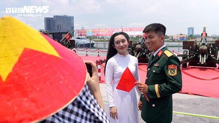 Già, trẻ, gái, trai... ai cũng mang bên mình hình ảnh lá cờ Tổ quốc để lưu giữ hình ảnh đặc biệt 10 năm mới có 1 lần tại bến Bạch Đằng. (Ảnh: Kim Thược)